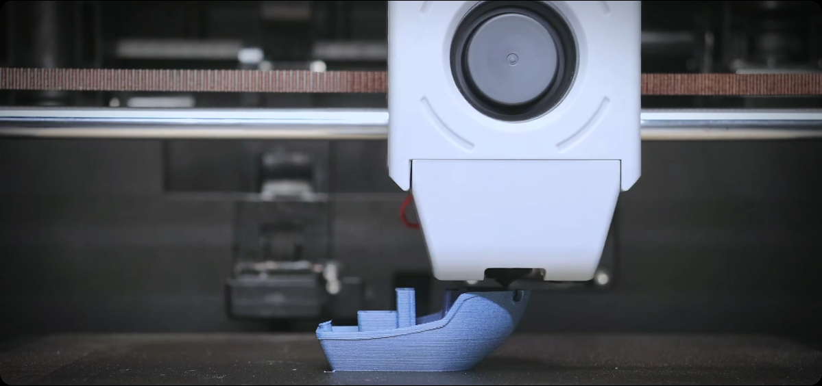 The 3D printer is printing a blue boat model
